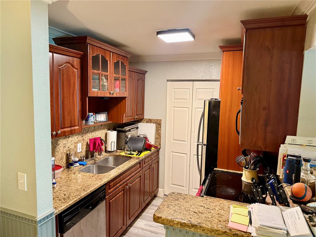 A kitchen features wood cabinets, granite countertops, a double sink, and stainless steel appliances — 455 ALT 19 S UNIT 47, PALM HARBOR, FL