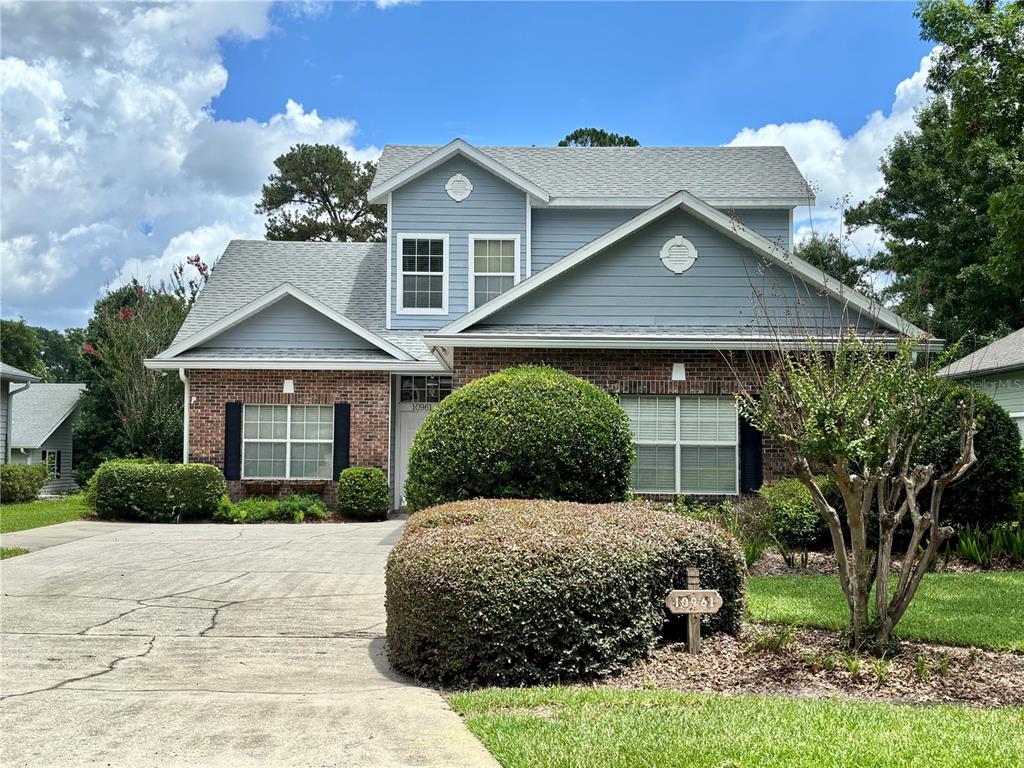 A two-story house with a brick and light blue siding exterior and a concrete driveway — 10961 PALMETTO BOULEVARD, ALACHUA, FL