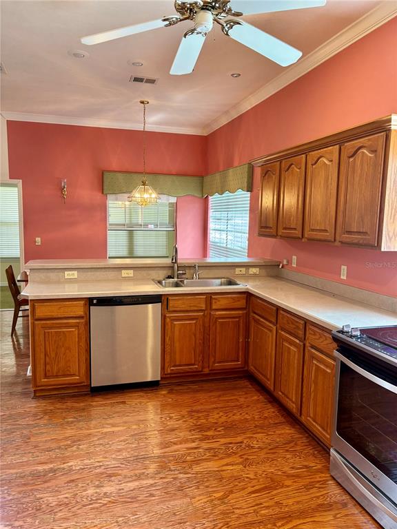 A kitchen features oak cabinets, stainless steel appliances, a ceiling fan, and salmon-colored walls — 10961 PALMETTO BOULEVARD, ALACHUA, FL