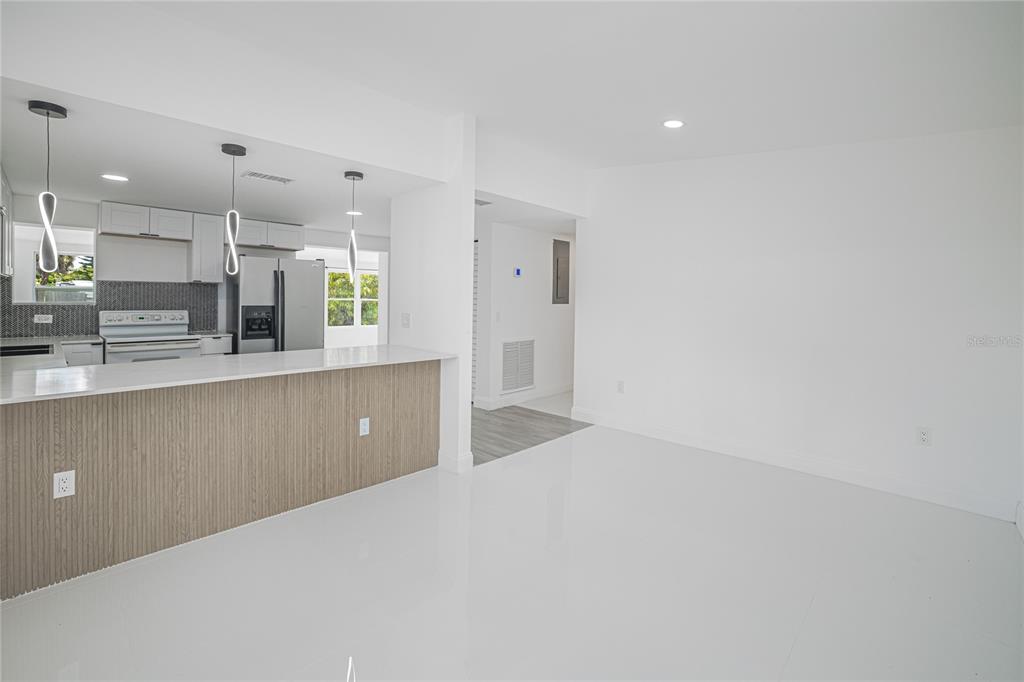 A bright, open-concept kitchen features a wood-paneled island, white cabinetry, and glossy tile flooring — 203 WATERWAY CIRCLE NE, PORT CHARLOTTE, FL