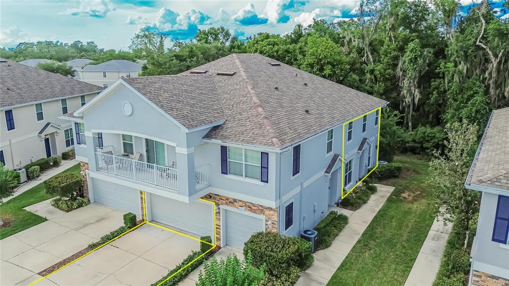 An aerial view shows the exterior of a light blue multi-story townhouse with garages — 714 ASHENTREE DRIVE, PLANT CITY, FL