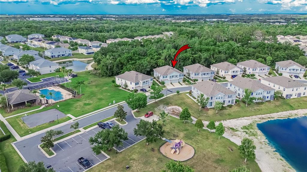 An aerial view shows a residential neighborhood with a playground, swimming pool, and lake — 714 ASHENTREE DRIVE, PLANT CITY, FL