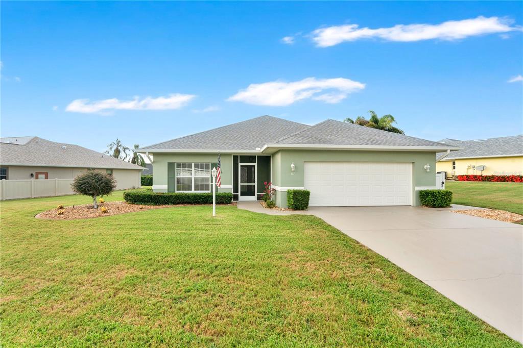 A single-story house with a green exterior, a two-car garage, and a large front lawn — 117 ROSEWOOD DRIVE N, LAKE PLACID, FL