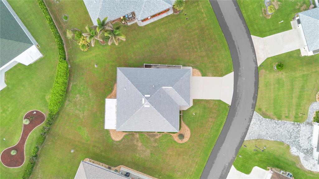 An aerial view shows a single-family home with a gray roof, driveway, and surrounding lawn — 117 ROSEWOOD DRIVE N, LAKE PLACID, FL