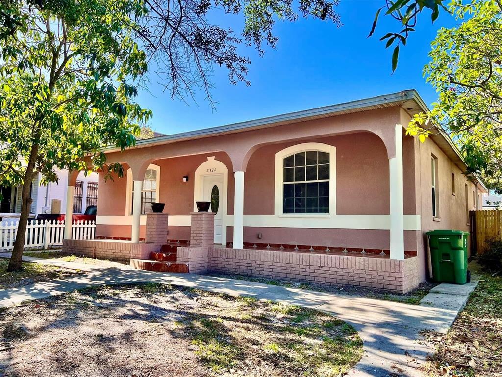 A single-story house with a covered front porch, arched openings, and a pink stucco exterior — 2324 W PALMETTO STREET, TAMPA, FL