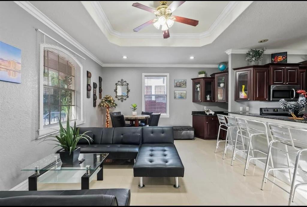 A living room and kitchen area with a black sectional sofa, breakfast bar, and tile — 2324 W PALMETTO STREET, TAMPA, FL