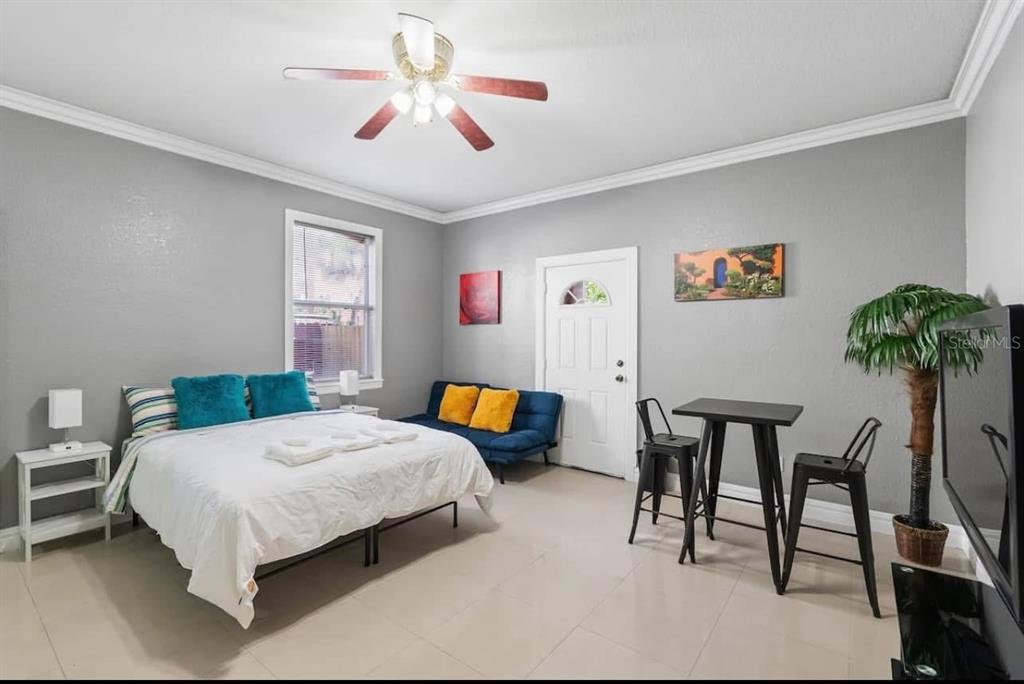 A bedroom with gray walls, a bed, a blue futon, and a small dining table — 2324 W PALMETTO STREET, TAMPA, FL