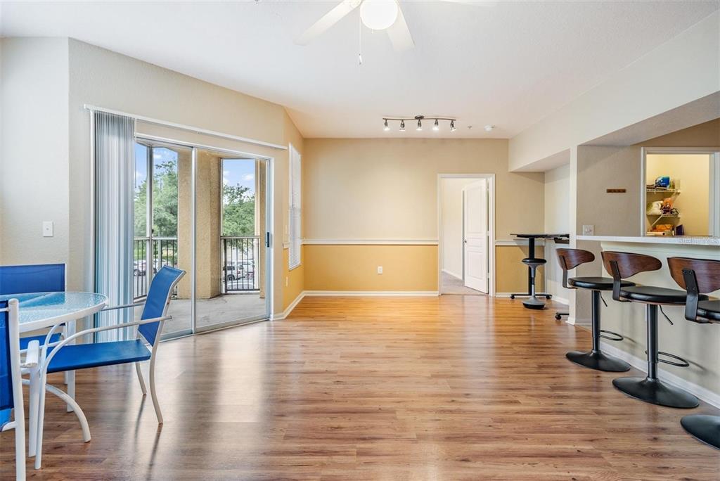 An open-concept dining area features wood-look flooring, a breakfast bar, and a sliding glass door — 5125 PALM SPRINGS BOULEVARD UNIT 8203, TAMPA, FL