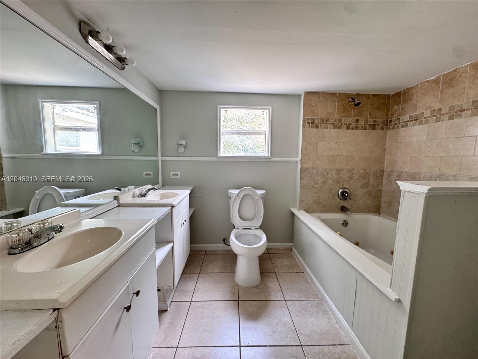 A bathroom features a double vanity, a toilet, and a tiled tub-shower combination — 1801 NE 50th St, Pompano Beach FL 33064, POMPANO BEACH, FL