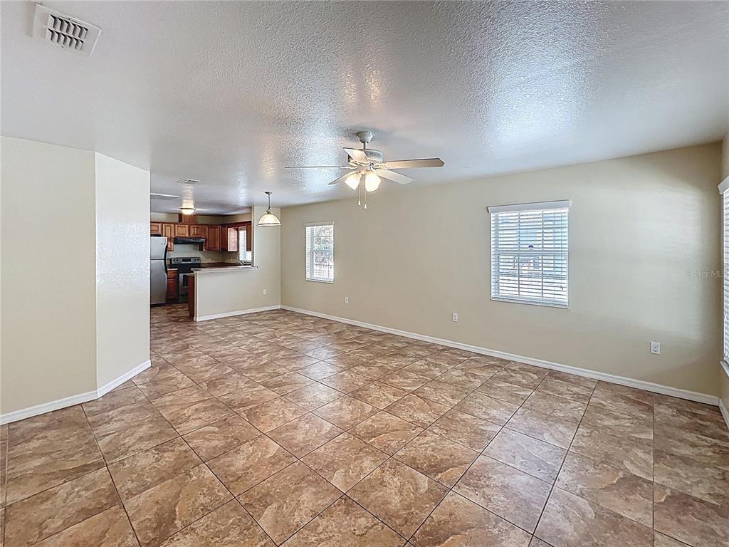 An open-concept living area features tan tile flooring, beige walls, and an adjacent kitchen — 838 N IOWA AVENUE, LAKELAND, FL