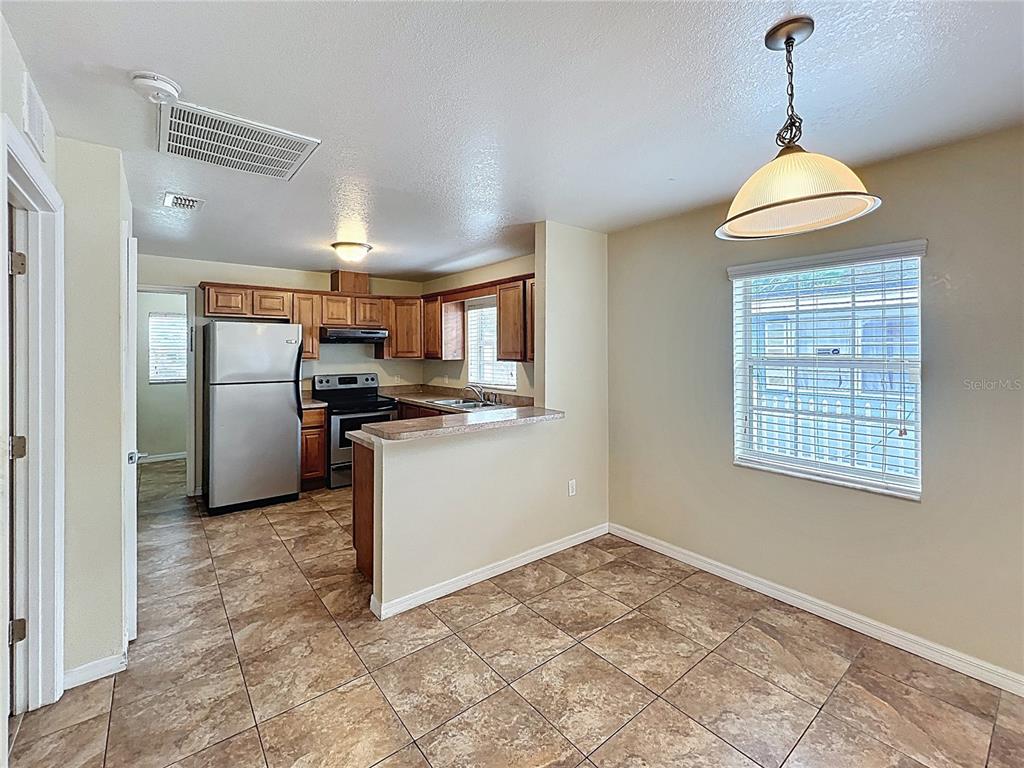 A kitchen with wood cabinets and stainless steel appliances opens to a tiled dining area — 838 N IOWA AVENUE, LAKELAND, FL
