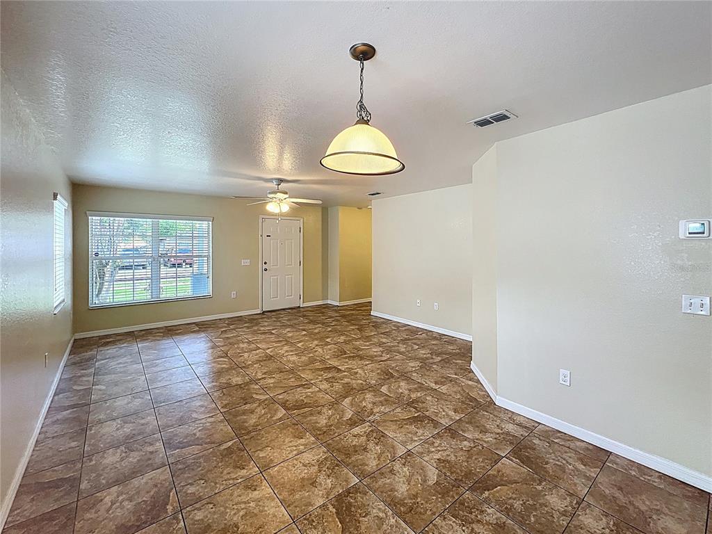 An open living area features tan tile flooring, a ceiling fan, and a pendant light — 838 N IOWA AVENUE, LAKELAND, FL