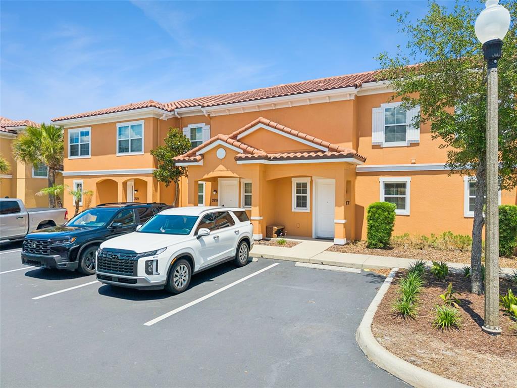 A two-story orange stucco townhouse with a tiled roof and two parked SUVs in front — 2617 BUGATTI COURT, KISSIMMEE, FL