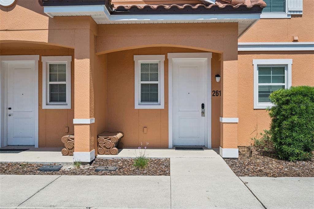 The exterior view shows a tan stucco townhouse entrance with a white door numbered 261 — 2617 BUGATTI COURT, KISSIMMEE, FL