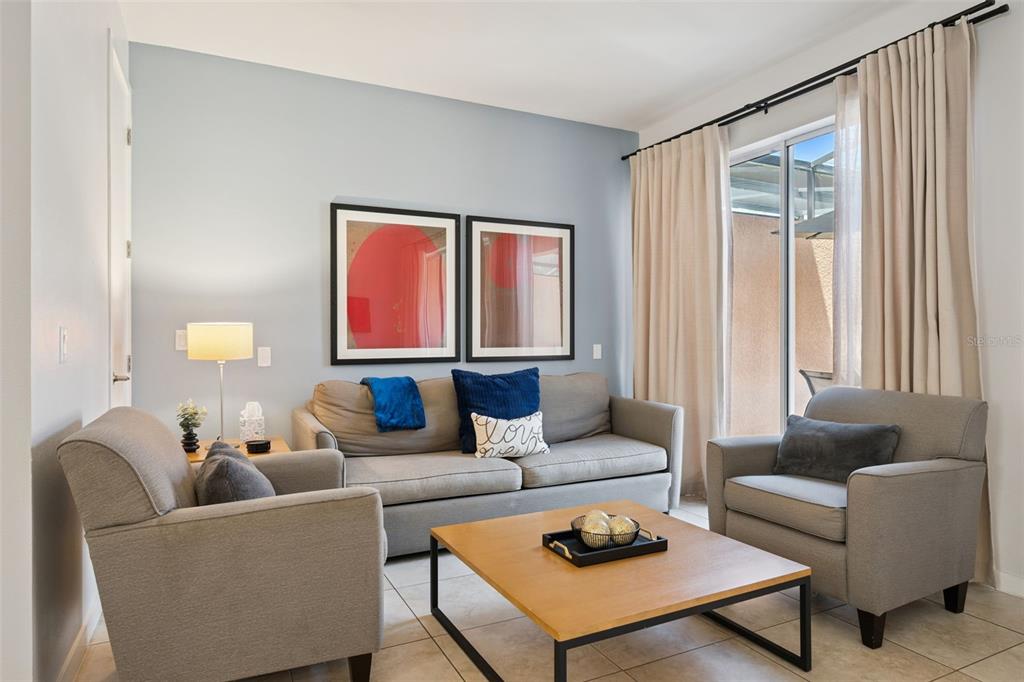 A living room features a gray sofa, two armchairs, a coffee table, and sliding glass doors — 2617 BUGATTI COURT, KISSIMMEE, FL