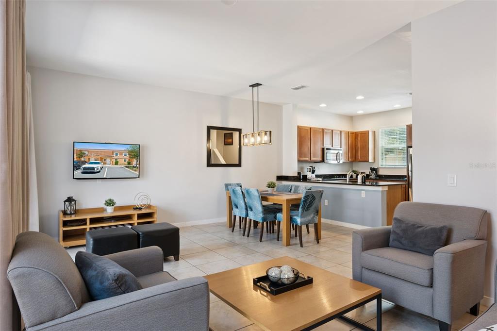 An open-concept living and dining area features tile flooring, gray furniture, and a kitchen — 2617 BUGATTI COURT, KISSIMMEE, FL