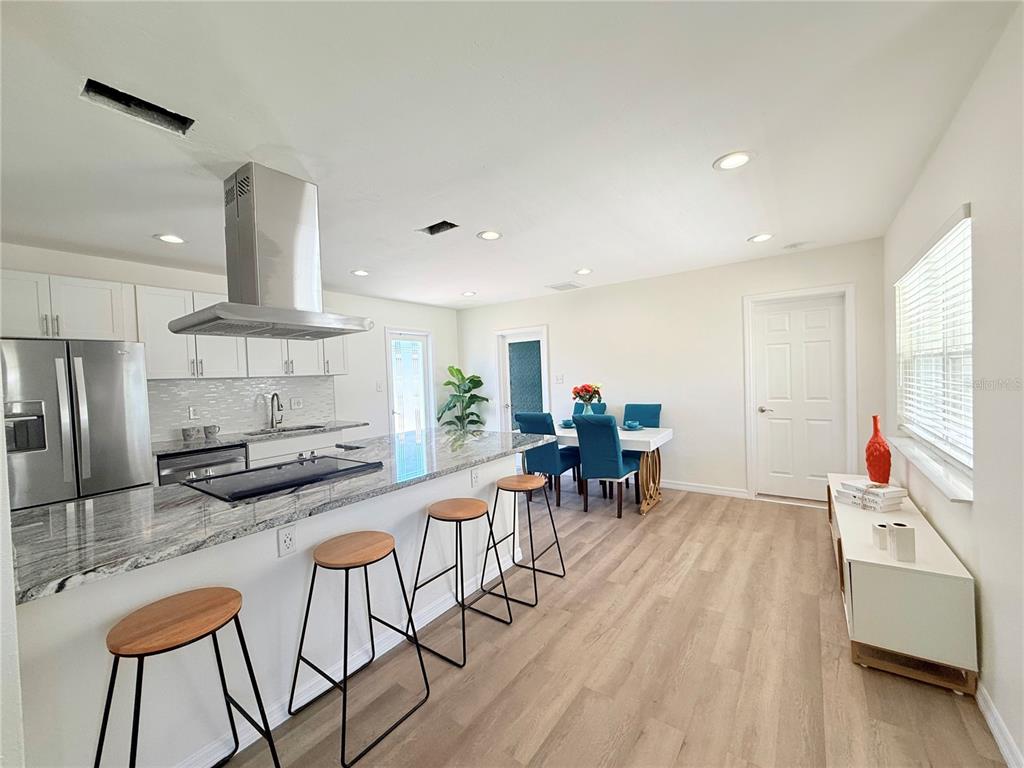A kitchen with a granite island, bar stools, and an adjacent dining area — 1500 77TH STREET N, ST PETERSBURG, FL