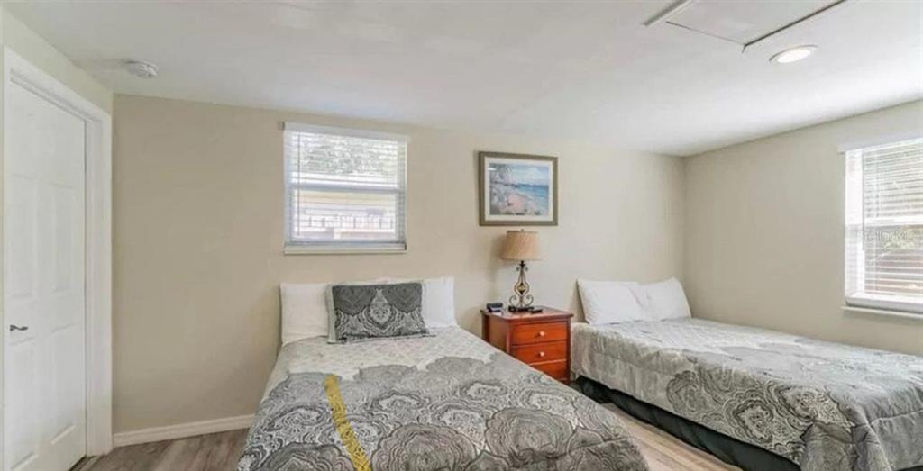 A bedroom features two beds with patterned bedding, a nightstand, and two windows — 1500 77TH STREET N, ST PETERSBURG, FL