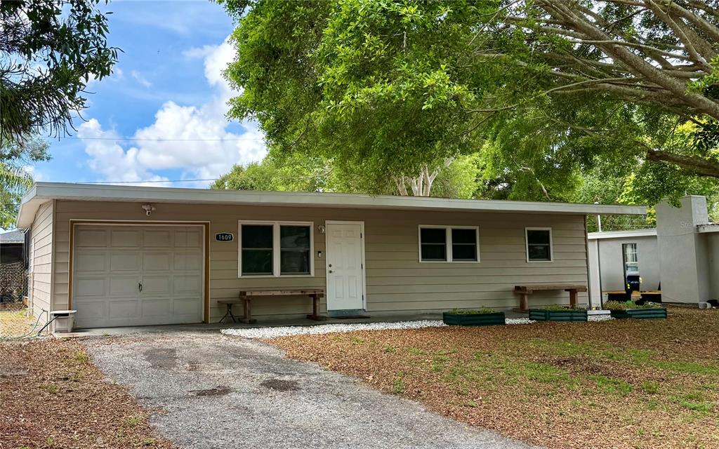 A single-story house with tan siding, a white front door, and an attached garage — 1609 SCOTT STREET, CLEARWATER, FL