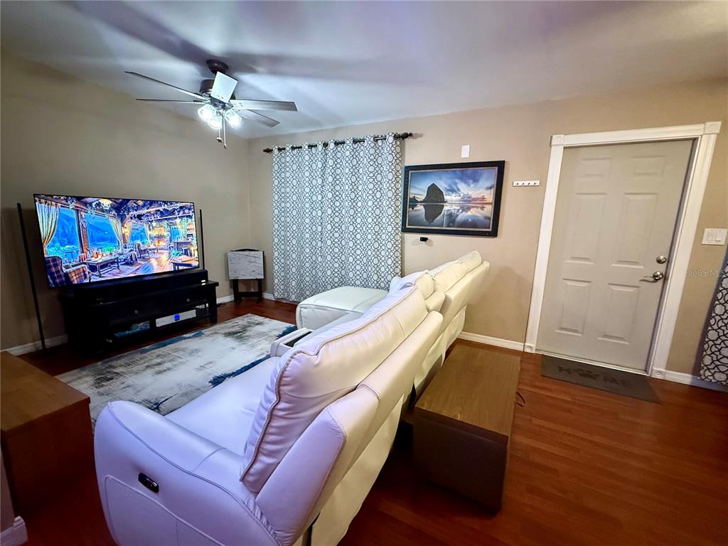 A living room features a white sectional sofa, a television on a stand, and wood flooring — 1609 SCOTT STREET, CLEARWATER, FL