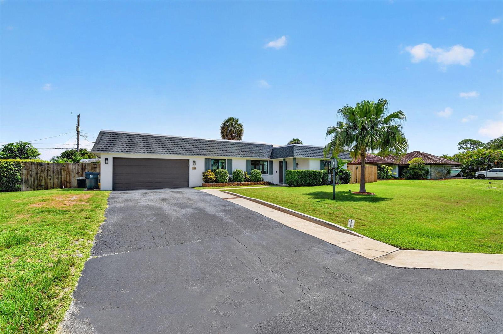 A single-story house with a dark shingled roof, white exterior, and an asphalt driveway — 110 W Coconut Drive, Lake Worth FL 33467, LAKE WORTH, FL
