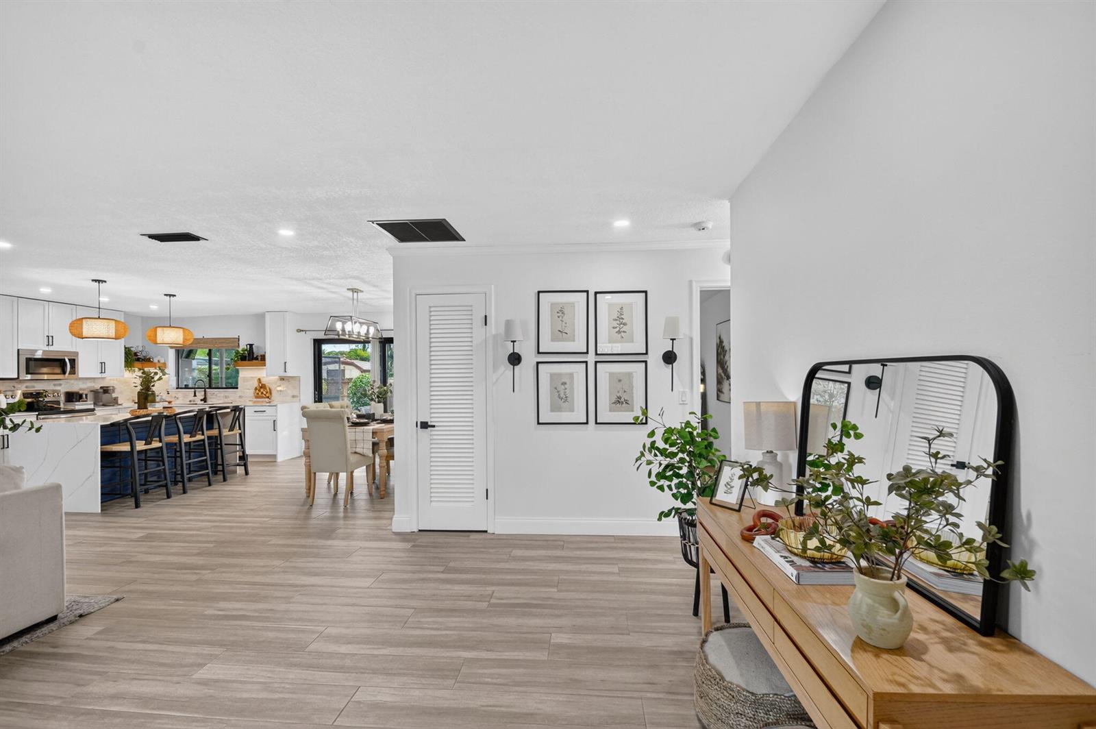 A bright, open-concept living area features wood-look tile flooring, a kitchen island, and a console — 110 W Coconut Drive, Lake Worth FL 33467, LAKE WORTH, FL