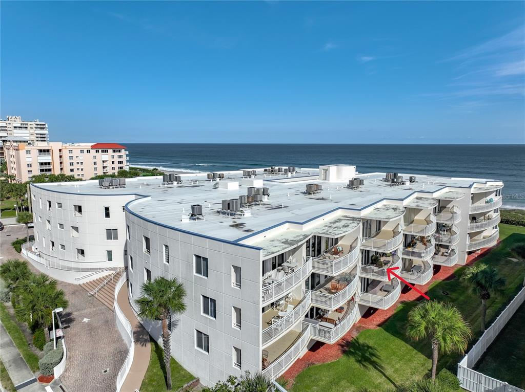 An aerial view of a multi-story beachfront condominium building with balconies and a flat roof — 601 N MIRAMAR AVENUE UNIT 205, INDIALANTIC, FL