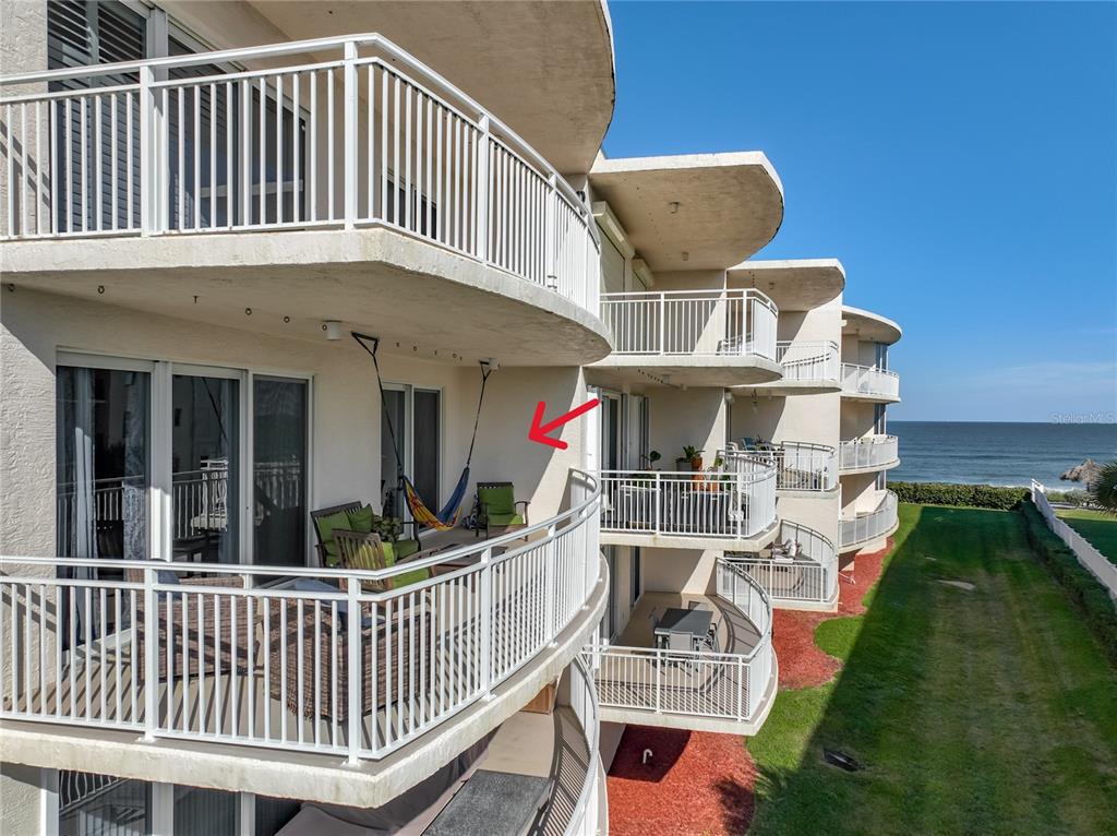 An exterior view of a multi-story building featuring curved balconies overlooking the ocean — 601 N MIRAMAR AVENUE UNIT 205, INDIALANTIC, FL