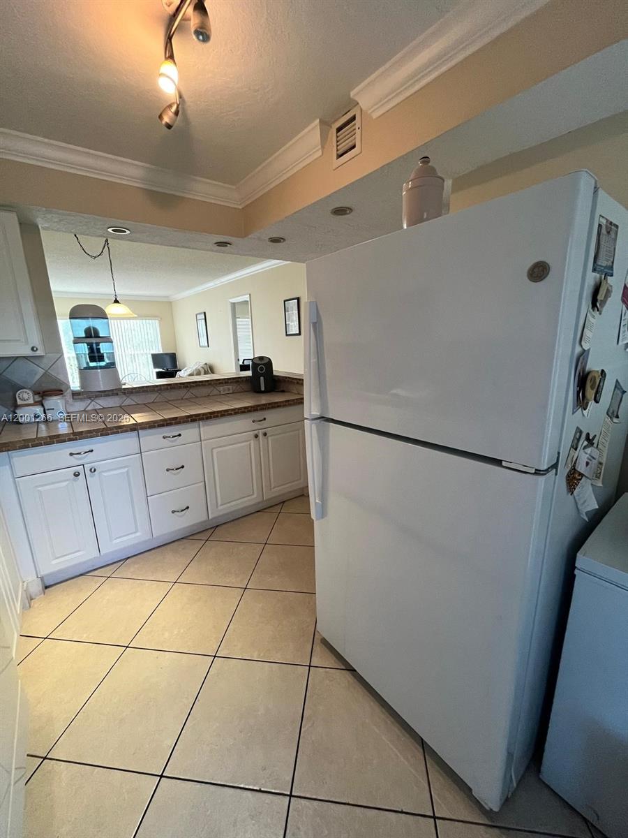 A white refrigerator stands in a kitchen with tiled floors and white cabinets — 3200 N Palm Aire Dr # 407, Pompano Beach FL 33069, POMPANO BEACH, FL