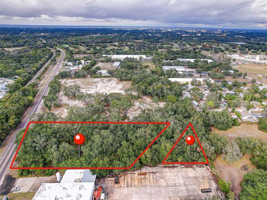 An aerial view shows two wooded lots outlined in red next to a paved industrial area — 6905 & 6907 ROWLETT PARK DRIVE, TAMPA, FL