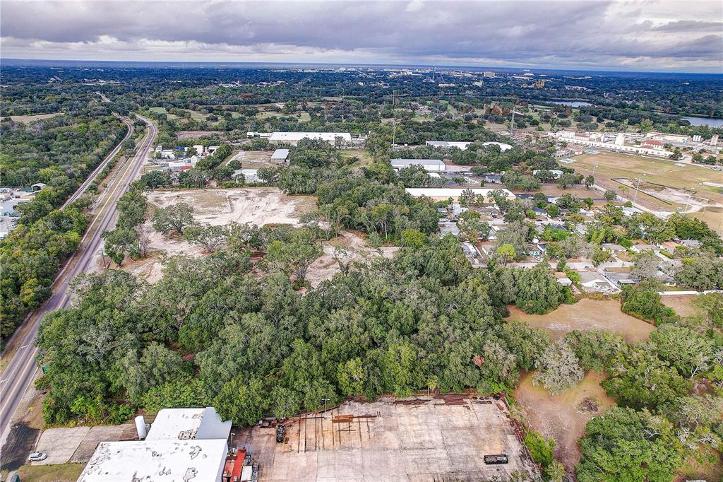 An aerial view shows a large, wooded lot adjacent to a road and industrial buildings — 6905 & 6907 ROWLETT PARK DRIVE, TAMPA, FL