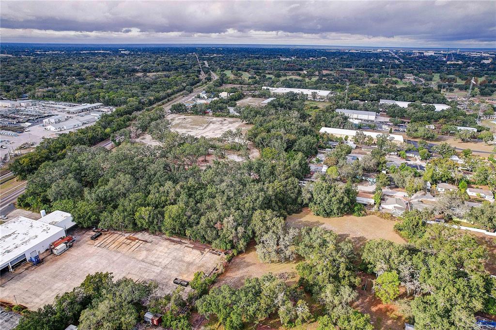 An aerial view shows a large, wooded lot adjacent to industrial buildings and residential areas — 6905 & 6907 ROWLETT PARK DRIVE, TAMPA, FL