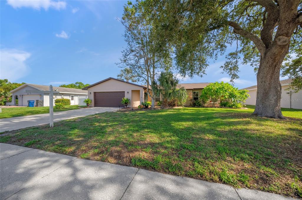 A single-story house with a brown garage, a large oak tree, and a grassy lawn — 911 SOUTHERN PINE LANE, SARASOTA, FL