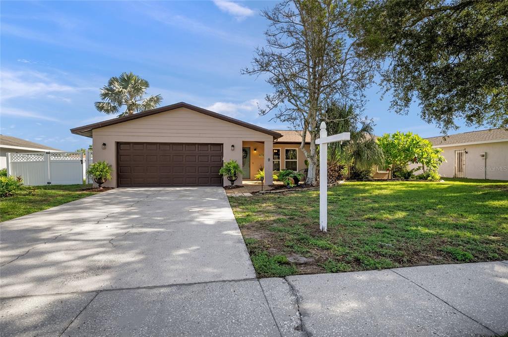 A single-story house with a brown garage door, a concrete driveway, and a front lawn — 911 SOUTHERN PINE LANE, SARASOTA, FL