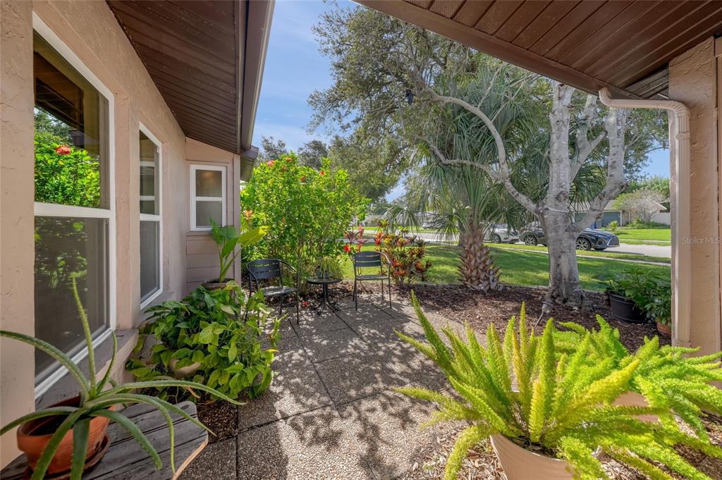 A paved patio area features two chairs, potted plants, and a view of the yard — 911 SOUTHERN PINE LANE, SARASOTA, FL
