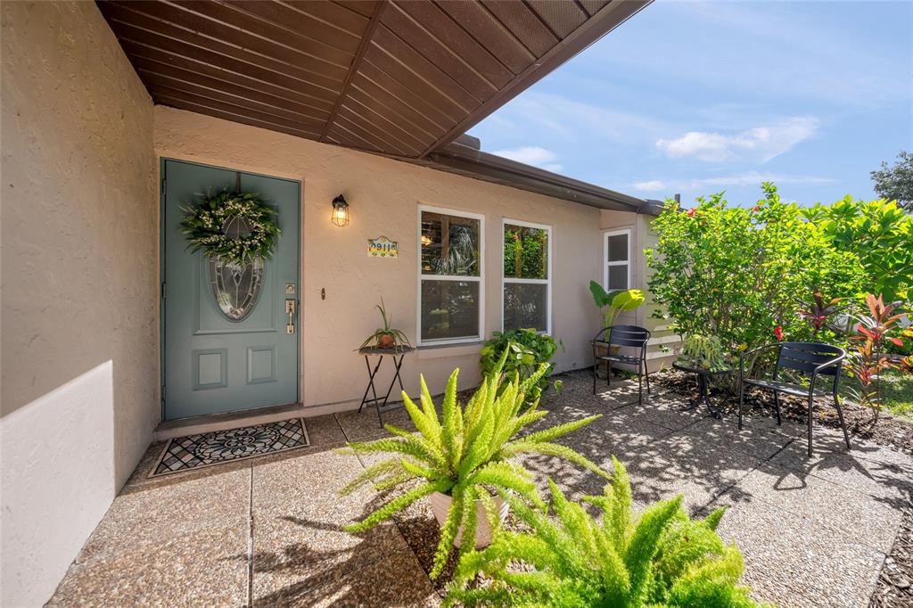 A front patio with a light blue door, two chairs, and potted plants — 911 SOUTHERN PINE LANE, SARASOTA, FL