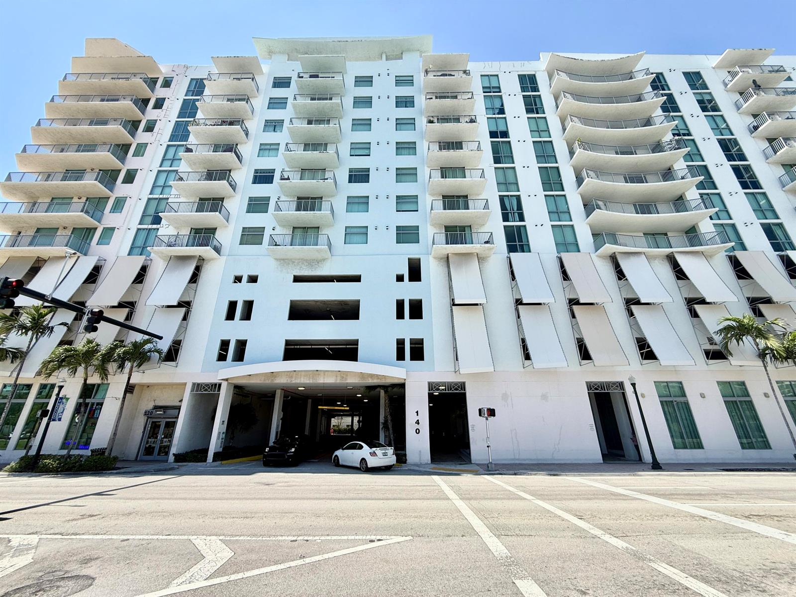 A low-angle exterior view of a multi-story apartment building with balconies and a parking entrance — 140 S Dixie Highway # 813, Hollywood FL 33020, HOLLYWOOD, FL
