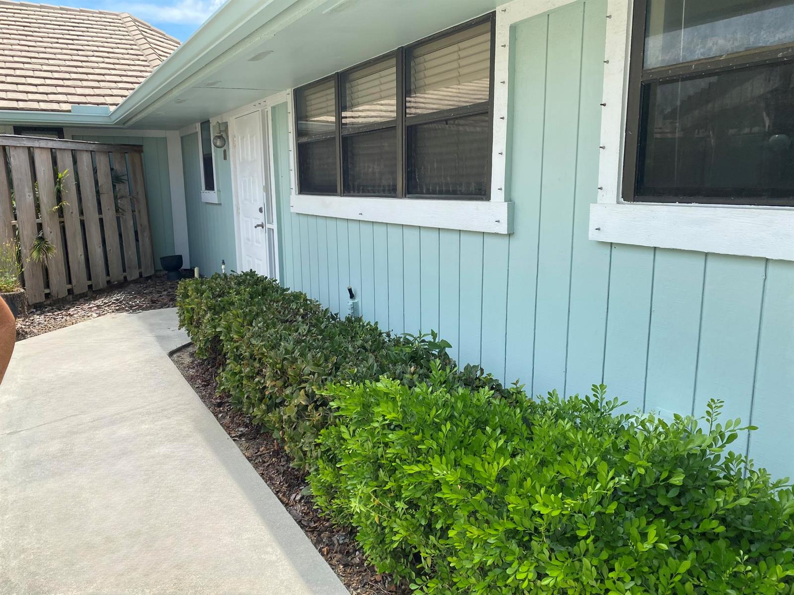 A light blue house exterior features a concrete walkway, a white door, and green hedges — 1127 E Seminole Avenue # 13d, Jupiter FL 33477, JUPITER, FL