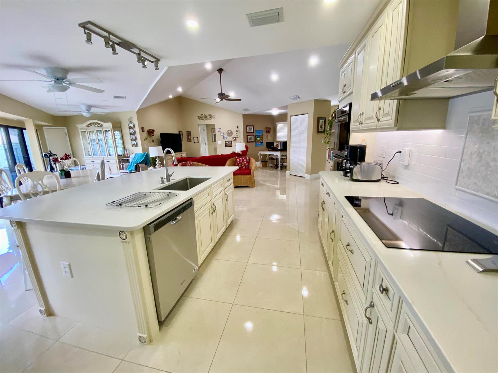 A kitchen with a large island, white cabinetry, and tile flooring opens to a living area — 1127 E Seminole Avenue # 13d, Jupiter FL 33477, JUPITER, FL