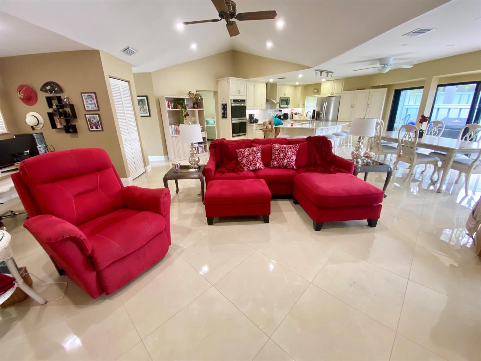 A bright open-concept living room features a red sectional, matching recliner, and tiled floors — 1127 E Seminole Avenue # 13d, Jupiter FL 33477, JUPITER, FL