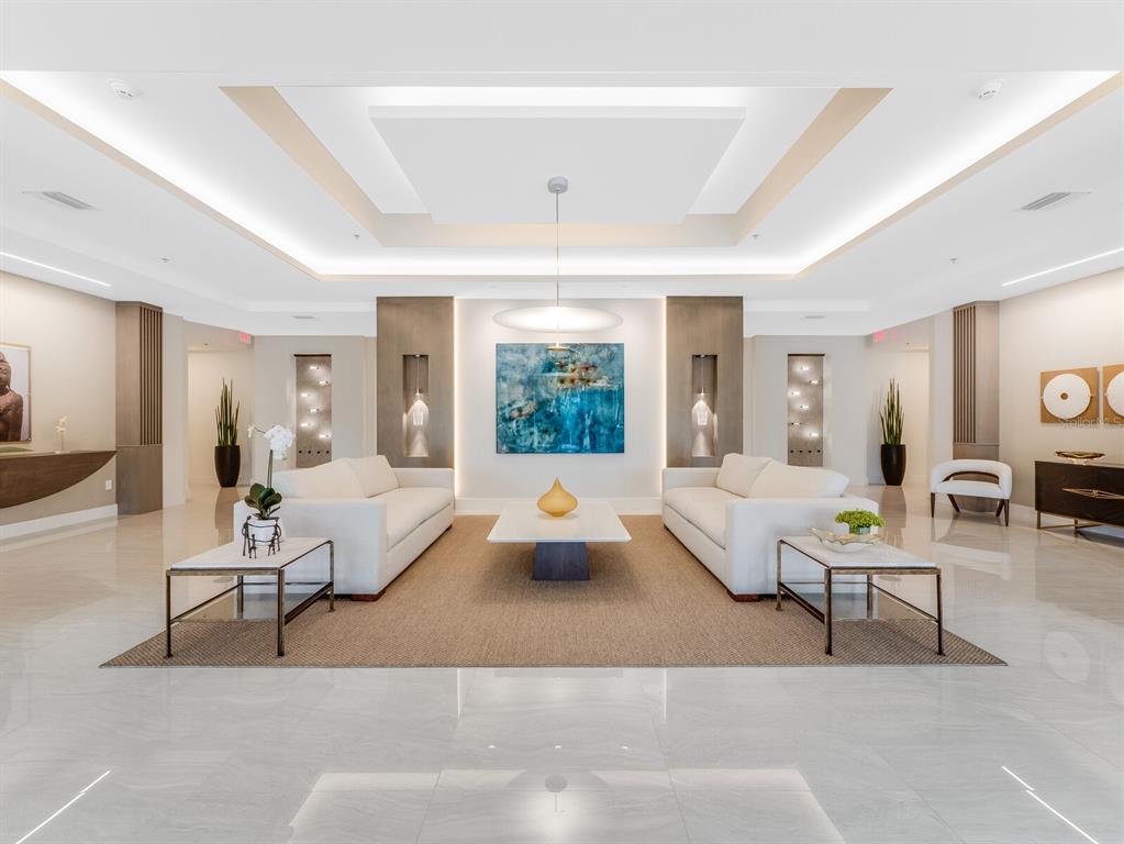 A modern, symmetrical lobby features two white sofas, a central painting, and polished tile floors — 3040 GRAND BAY BOULEVARD UNIT 225, LONGBOAT KEY, FL