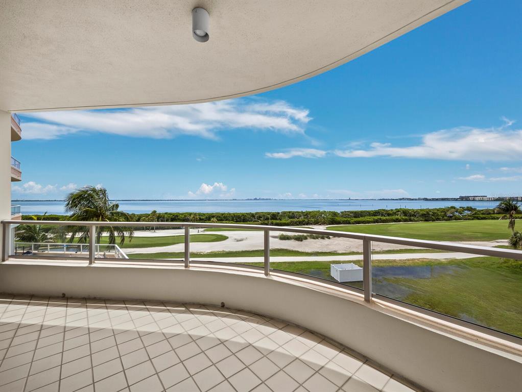 A curved balcony with tiled flooring overlooks a golf course and a large body of water — 3040 GRAND BAY BOULEVARD UNIT 225, LONGBOAT KEY, FL