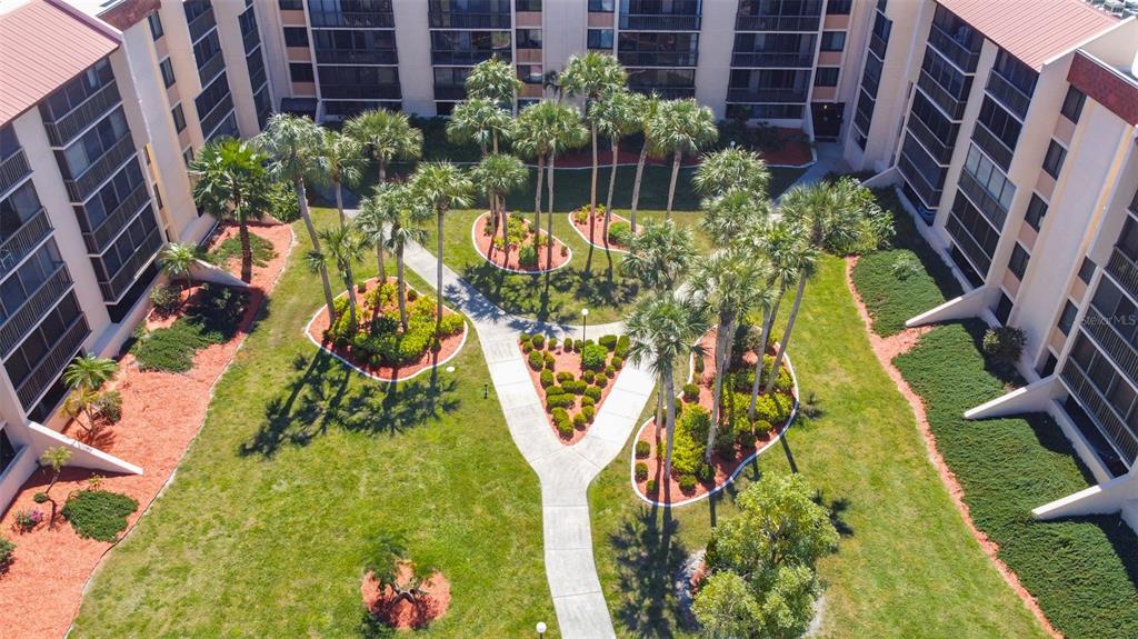 An aerial view of a landscaped courtyard surrounded by multi-story residential apartment buildings — 3006 CARING WAY UNIT 523, PORT CHARLOTTE, FL