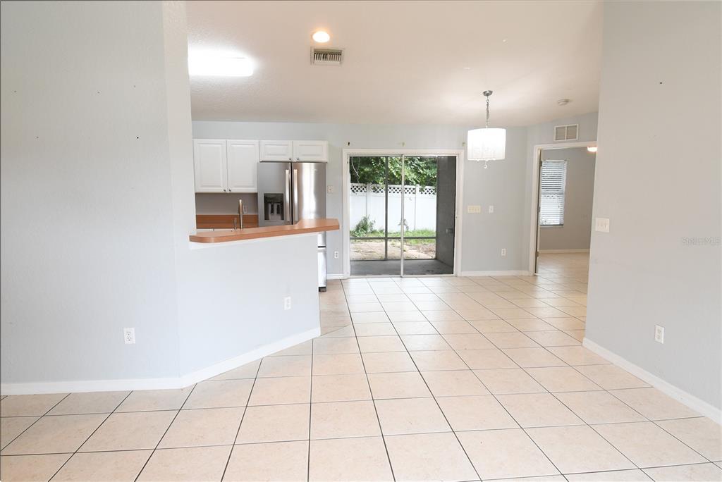 An open-concept kitchen and dining area features tile flooring, white cabinets, and a sliding door — 407 CIERRA OAKS CIRCLE, LADY LAKE, FL