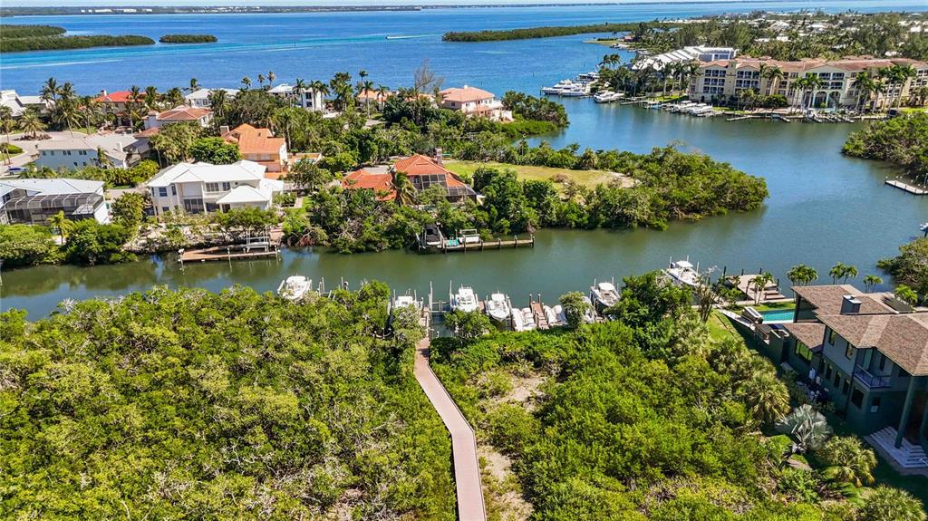 An aerial view shows waterfront homes, a wooden boardwalk, and several boats docked in a canal — 6322 LAGUNA DRIVE UNIT 1, LONGBOAT KEY, FL