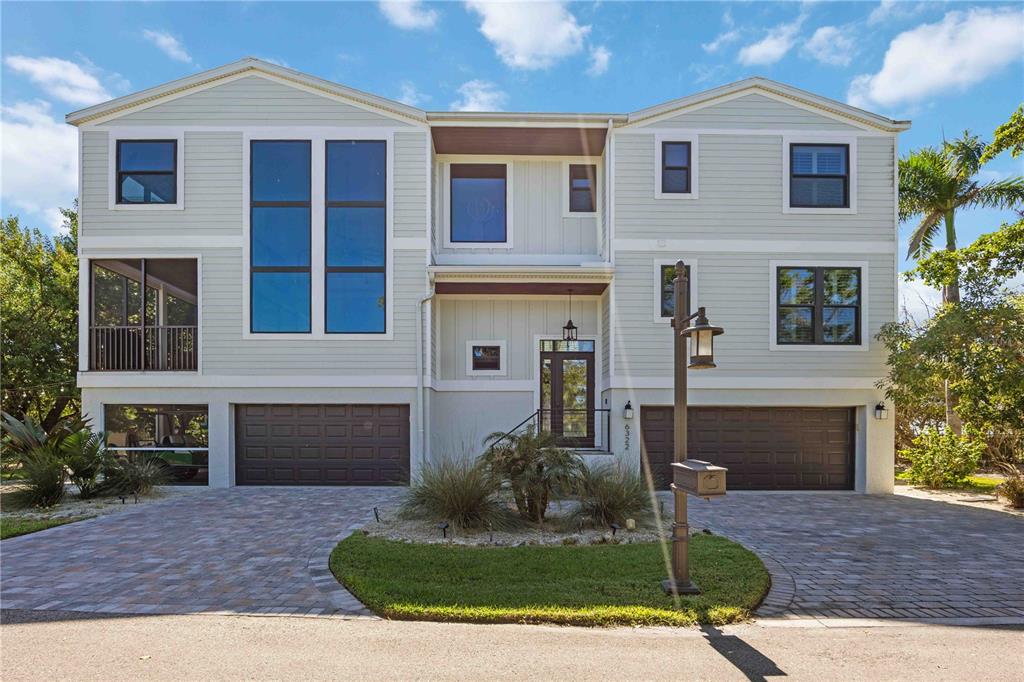 A three-story house with light siding, two garage doors, and a paved driveway — 6322 LAGUNA DRIVE UNIT 1, LONGBOAT KEY, FL