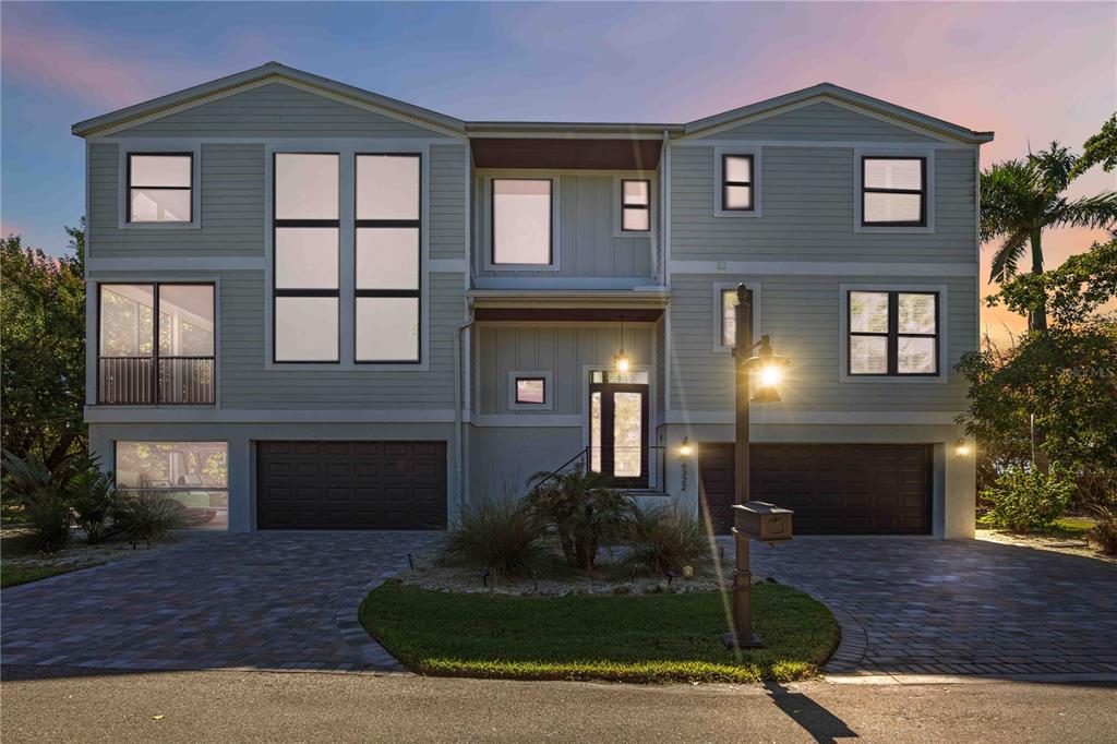 A three-story house with light green siding, two garages, and a paved driveway — 6322 LAGUNA DRIVE UNIT 1, LONGBOAT KEY, FL