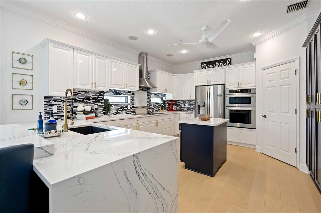 A modern kitchen features white cabinets, a dark blue island, and a marble-topped peninsula — 6322 LAGUNA DRIVE UNIT 1, LONGBOAT KEY, FL