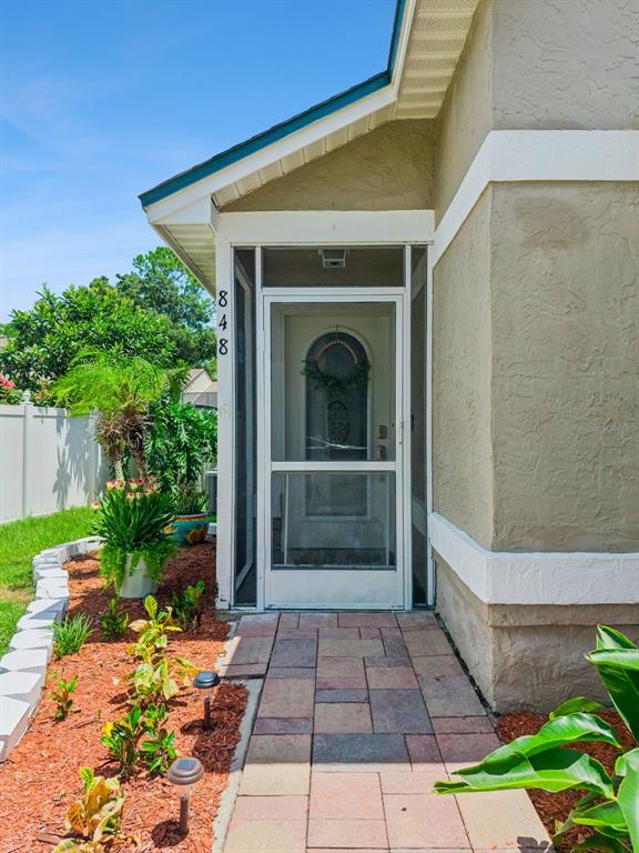 A paved walkway leads to a screened front door with a wreath on a house — 848 HEATHER GLEN CIRCLE, LAKE MARY, FL