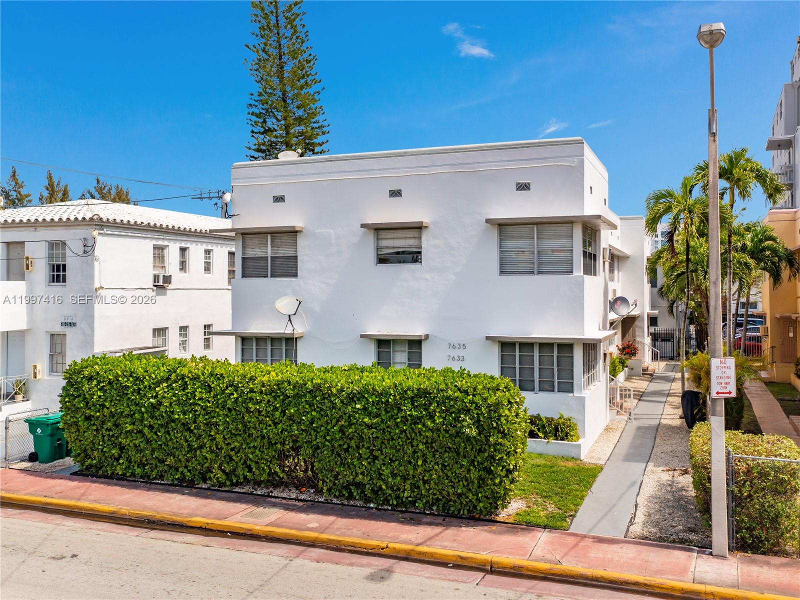 A two-story white apartment building features a large hedge and a sidewalk entrance — 7635 Dickens Ave, Miami Beach FL 33141, MIAMI BEACH, FL